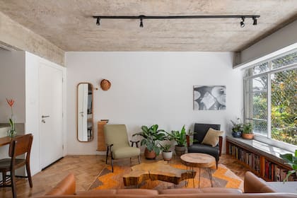 La puerta de entrada desemboca directamente en el living, pero los ventanales corridos eliminan cualquier sensación de estar amuchados. La pared se dejó libre para funcionar como pantalla de cine.