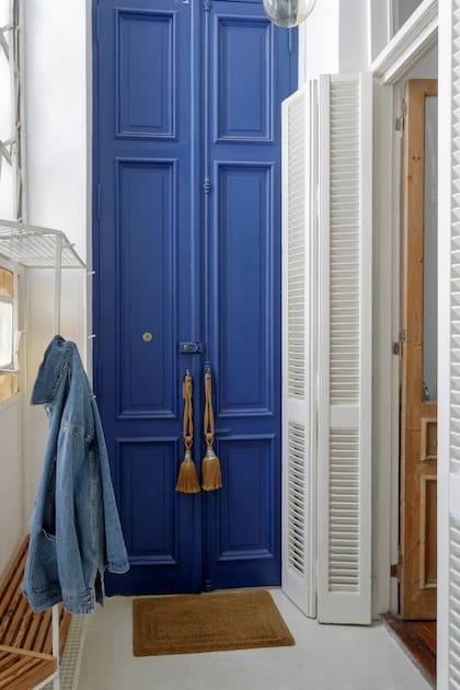 La puerta de entrada, original, es altísima; la pintaron de azul para darle todavía mayor relevancia. Los postigos de hojas angostas fueron restaurados y pintados de blanco.