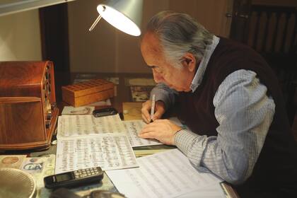 La radio antigua dominando las partituras escritas a mano en la mesa de trabajo de Manolo Juárez