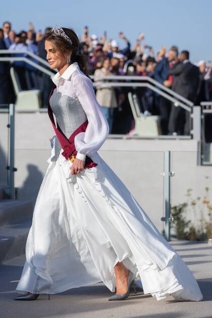 La Reina, con una propuesta del diseñador jordano Laith Maalouf cargada de significado: los botones de la camisa –semitransparente y con mangas abullonadas– representan la estrella de siete puntas de Jordania, símbolo de unidad y esperanza; la falda –larga– tiene bordadas espigas de trigo, otro símbolo del país; y el corset –ceñido e irregular– alude a la protección y a la fuerza de estos últimos 25 años.