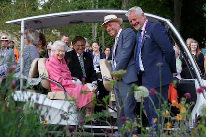 La reina Isabel de Gran Bretaña sonríe con el diseñador de jardines Joe Swift y Mark Gregoy, embajador de RHS, en 'BBC Studios Our Green Planet and RHS Bee Garden', mientras recorre el jardín en un buggy con el presidente de RHS, Keith Weed, durante una visita real a RHS Chelsea Flower Show, el lunes 23 de mayo de 2022 .RHS / Luke MacGregor