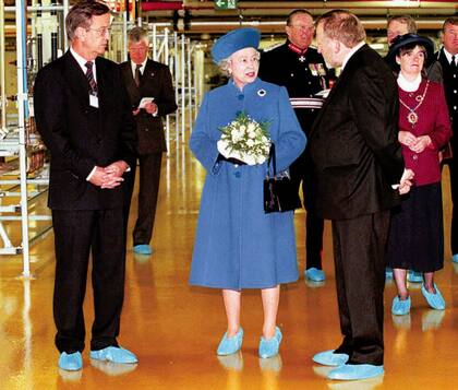 La reina Isabel II de Gran Bretaña, con zapatos protectores mientras recorre la nueva fábrica de Siemens en Wallsend, cerca de Newcastle el viernes 23 de mayo de 1997. La reina inauguró la enorme fábrica de microchips con una ceremonia oficial histórica transmitida a través de Internet en todo el mundo. Se cree que esta fue la primera vez que la Reina se vio y escuchó en vivo a través de Internet