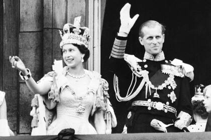 La reina Isabel II de Gran Bretaña (L) y el príncipe Felipe de Gran Bretaña, duque de Edimburgo, saludan a la multitud desde el balcón del Palacio de Buckingham, luego de su coronación, el 2 de junio de 1953