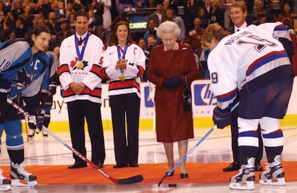 La reina Isabel II realizó el mismo saque de honor en un partido de pretemporada durante una gira que realizó por Canadá cuando se cumplía su Jubileo de Oro. En la imagen, se la ve rodeada por Markus Naslund (derecha) Mike Ricci (izquierda), capitanes de los Vancouver Canucks y de los San Jose Sharks, respectivamente.