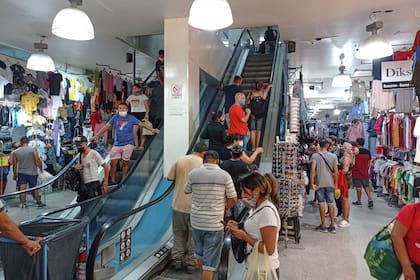 Las escaleras mecánicas y los pasillos de uno de los paseos de compras de La Salada; el sentido de circulación está marcado en el piso, pero pocos lo cumplen