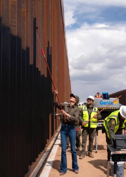 La secretaria Noem participó con un rodillo del trabajo de pintura en el muro