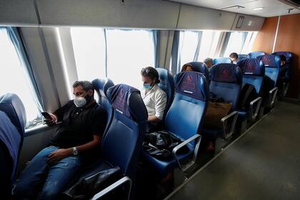Pasajeros de un ferry utilizan barbijos y mantienen distancia social al viajar con el asiento del pasillo vacío, en Capri, Italia