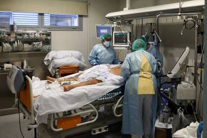 Trabajadores médicos atienden a un paciente infectado por COVID-19 en la unidad de cuidados intensivos (UCI) del Hospital Universitario Infanta Sofía, en Madrid, España