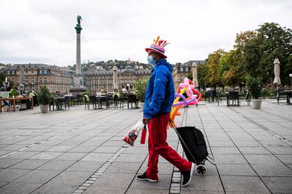 Un artista de globos camina por la Schlossplatz vacía, con una máscara facial, en Stuttgart, Alemania