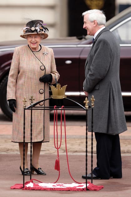 La soberana conversa con el autor del libro, Hugo Vickers, en un acto celebrado en Londres en febrero de 2012