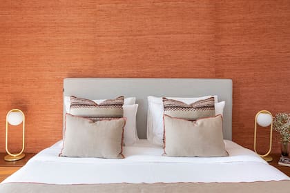 La suite tiene revestimiento textil 'Gold Coast Silk' (Phillip Jeffries) y lámparas doradas 'C Ball T' (Blux). Almohadones con género 'Mamounia' (Güell Lamadrid) y 'Eric Clapton' (Zeconzeta).