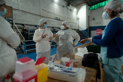 La supervisora ​​de enfermería Paola Almirón, centro derecha, organiza una campaña de vacunación contra el COVID-19 en un gimnasio en las afueras de Buenos Aires, Argentina, el viernes 9 de julio de 2021.  (AP Foto/Víctor R. Caivano)