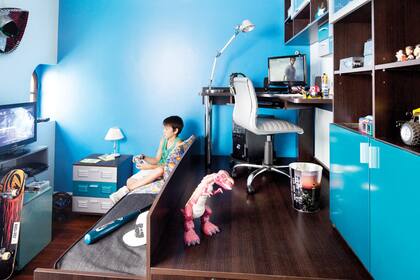 La tarima es una estructura con peldaños/cajones; escritorio de patas metálicas con alzada y biblioteca con puertas de madera y de vidrio.