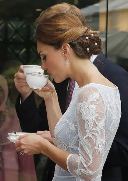 La taza de té se sostiene por el asa con el índice y el pulgar y el meñique siempre queda adentro
