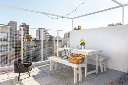 En la terraza, juego de mesa y bancos plegables. Cesto de fibras naturales (Claudia Adorno). Mantel estampado (Petite Margot).