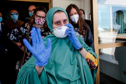 La trabajadora voluntaria italiana Silvia Costanza Romano, que fue secuestrada en Kenia a fines de 2018, con una máscara facial, saluda a su llegada al aeropuerto militar de Roma Ciampino