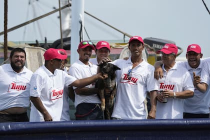 La tripulación del atunero mexicano María Delia posa para las fotos con Bella, la perra del australiano Timothy Lyndsay Shaddock, ambos rescatados de un catamarán dañado en el Océano Pacífico,
a su llegada al puerto de Manzanillo, México, el martes 18 de julio de 2023