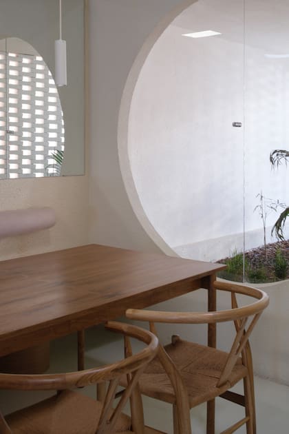 La ventana circular –con un paño batiente– da al patio delantero. Mesas y sillas de petiribí (Wollstudio).