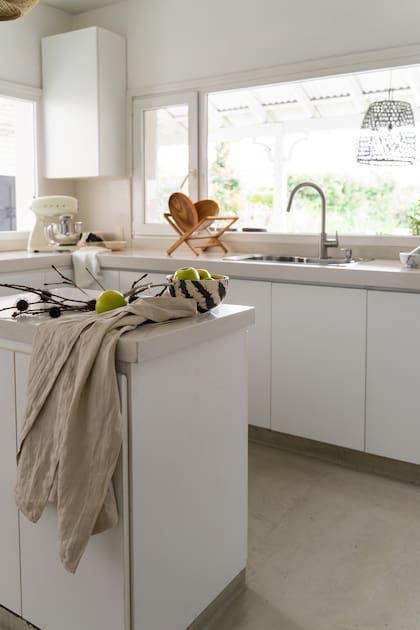 La ventana de la cocina da al jardín, algo que ilusionaba mucho a Carolina desde el primer día. Sobre la isla, camino de lino y bowls de cerámica (Tiendas Landmark).