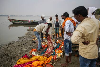 La gente se prepara para incinerar el cuerpo de una mujer hindú a orillas del río Ganges en las afueras de Varanasi, una de las ciudades más sagradas del hinduismo, India
