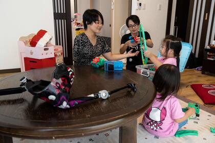 La violinista japonesa Manami Ito con sus hijas Miu y Mei y su esposo Yuki. Se ve el brazo protésico sobre la mesa en su residencia en Shizuoka