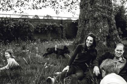 La viva imagen de la felicidad: los duques de Cambridge, relajados en los jardines del Palacio de Kensington mientras sus hijos, el príncipe George y la princesa Charlotte, juegan con su perro Lupo.