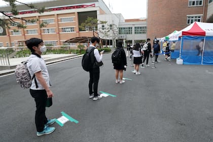 Hacen cola manteniendo distancia para el ingreso al edificio