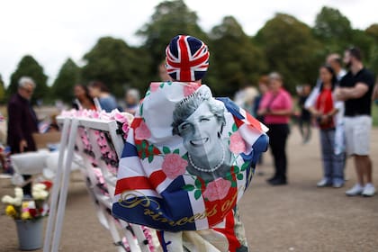 Un hombre envuelto en la bandera nacional británica con una fotografía de la princesa Diana de Gran Bretaña en un homenaje en el 25 aniversario de la muerte de la princesa de Gales, frente al Palacio de Kensington, en el centro de Londres