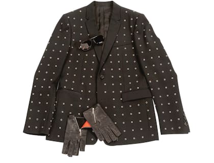 Lagerfeld y su singular estilo: cuello de camisa alto, saco y corbata negra, anteojos oscuros y mitones. Todas esas prendas son parte de la subasta. La chaqueta Dior Homme de gabardina de lana que luce en la imagen tiene un precio base de 800 dólares.