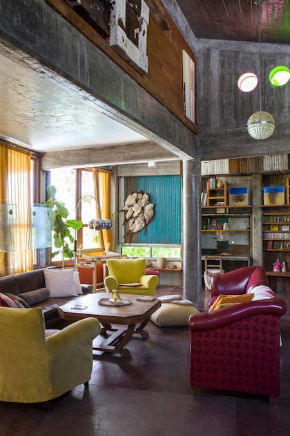 Lámpara de cristal checo y mesa ratona art déco, ambas de mercados de pulgas. Sillones heredados con fundas ajustables en terciopelo amarillo (Casa Almacén). Sobre la pared turquesa, una obra textil de Carmela “Pájaros”.