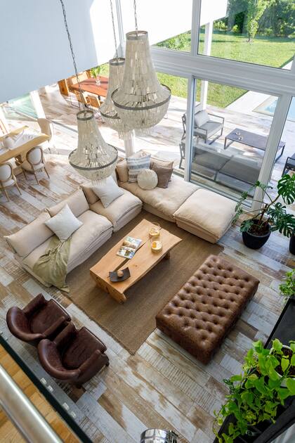 Lámpara de techo, estantería, puf y sillones (Landmark). Alfombra tejida en telar (Awanay). Manta de gasa sobre el sillón (Lote Propio).