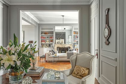 Como en las entradas de hotel, la mesa de ébano de Madagascar ostenta siempre un ramo enorme de flores, entre libros, velas y sulfuros de colección. Wing chairs inglesas tapizadas en lino (Zanav).