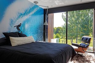 Para el dormitorio masculino, se eligió ploteo de surf como cabecera de cama. Lámpara Tolomeo de techo (Alejandro Lo Grasso) y sillón Eames (Paul French Gallery).