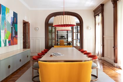Lámparas colgantes de la marca Weplight (Iluminación Agüero), mesa a medida con tapa de Neolith (Urbano Estudio), sillas tapizadas (Galería Ensemble). Sillones dobles y vajillero (todo de Mesopotamia) con tapa de Travertino (Tamoni) y obra (Espacio Pinasco).
