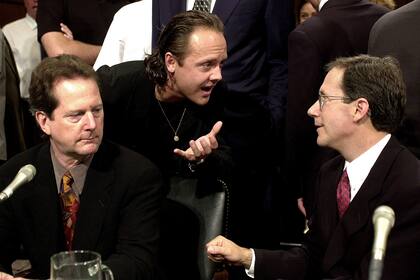 Lars Ulrich, en el centro, miembro de la banda de rock Metallica, habla con el director ejecutivo de Napster, Hank Barry, a la derecha, durante una audiencia del Comité Judicial del Senado en Capitol Hill el martes 11 de julio de 2000