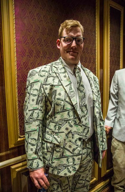 Un jugador audaz cubierto en un traje con billetes de dólar posa en el ascensor del Bellagio de Las Vegas.