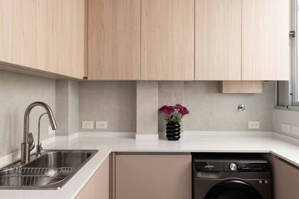 Las alacenas retoman el lenguaje del mueble del comedor realizado en melamina simil madera. Sobre el lavarropas, se oculta la caldera. Mesada es Silestone y grifería de Ponthus.