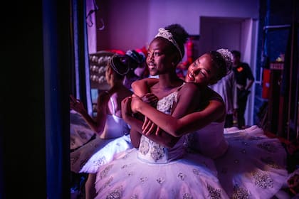 Las bailarinas Pauline Okumu (C) y Natalia Como (R) se abrazan en el backstage durante la producción del 'Cascanueces', un ballet clásico que se representa tradicionalmente en el período navideño, en el Teatro Nacional de Kenia en Nairobi, el 2 de diciembre de 2023.