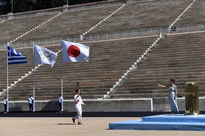 Las banderas de Grecia, de Japón y la olímpica flamean durante la ceremonia de entrega de la llama olímpica que se realizó en Atenas pese a la pandemia de coronavrus