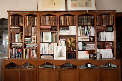 Las bibliotecas con arcos de estilo Tudor tienen espacio de guardado y vitrinas que se iluminan desde el interior, donde Mónica conserva gran cantidad de objetos: desde adornos hasta máquinas de escribir, pasando por un ventilador antiguo, fotos y recuerdos