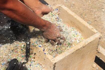 Las botellas, que son la materia prima para elaborar el concreto, se trituran para formar bolas y se lleva a la obra en enormes bolsas negras
