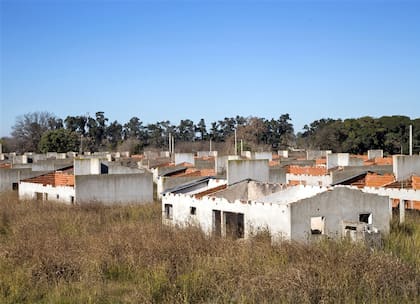Las casas del plan federal en el barrio La Perla no tienen techos ni aberturas, y están rodeadas de yuyos