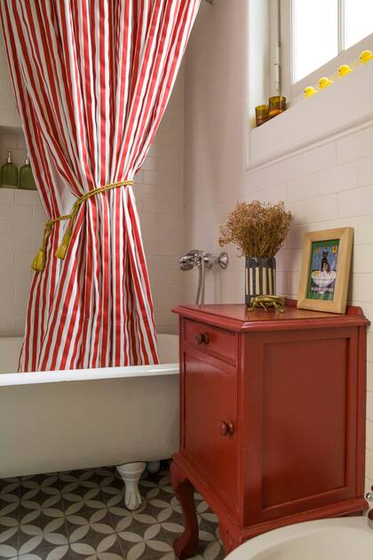 Las cortinas de baño rayadas hacen alusión a la carpa de un circo y el mueblecito de madera se pintó a tono.