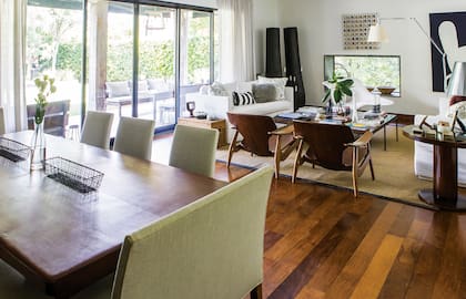 Las cortinas de lino, como los tapizados de las sillas y banquetas dobles de la mesa del comedor, son de Compañía del Comercio. El espacio integrado es amplio y luminoso, lo cual ofrece la posibilidad de usar muebles más pesados o de tonalidades más oscuras.