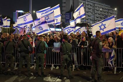 Las fuerzas de seguridad israelíes protegen una barrera mientras activistas de izquierda ondean banderas nacionales durante una manifestación antigubernamental en Tel Aviv, el 2 de marzo de 2024