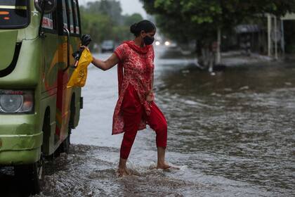 Una mujer desciende de un autobus en una calle inundada en Jammu