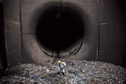 Un operario retira basura del canal aliviador del arroyo Maldonado, donde cada día sacan decenas de toneladas de residuos. Foto:Santiago Filipuzzi