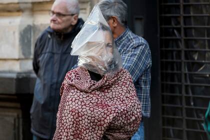 Una mujer con una improvisada protección se acerca al banco para cobrar la AUH en la ciudad de Rosario, 3 de abril