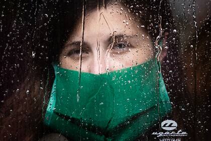 En un día lluvioso en la ciudad de Buenos Aires y en medio de la pandemia, una joven viaja en colectivo usando tapaboca, 4 de mayo