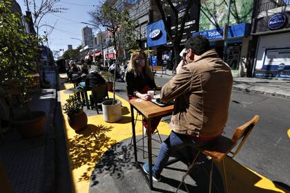 Fernando Grone y Cecilia Mitigueri toman un café sobre una de las mesas de la calle con demarcaciones para la distancia social